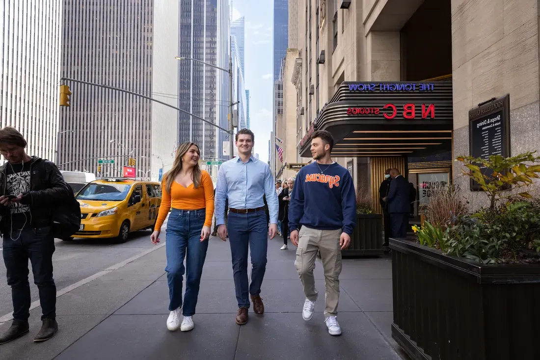 Three students walk down the street in New York City.